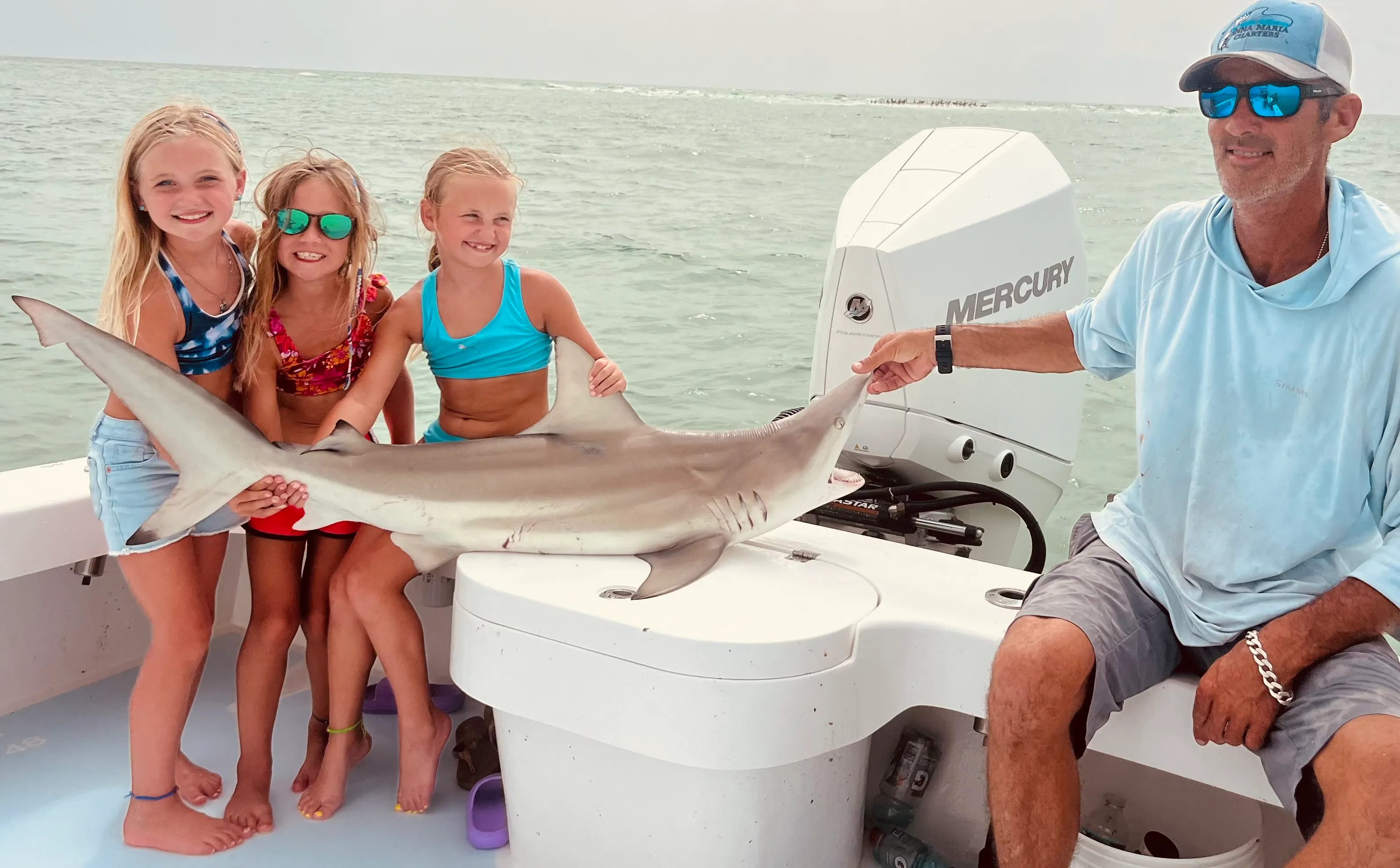 Kids and Captain David holding a small shark on the boat